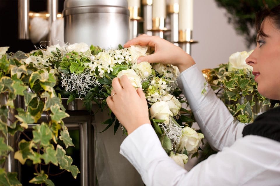 Woman in suit arranging flowers for funeral FIT Social Media Marketing for Funeral businesses